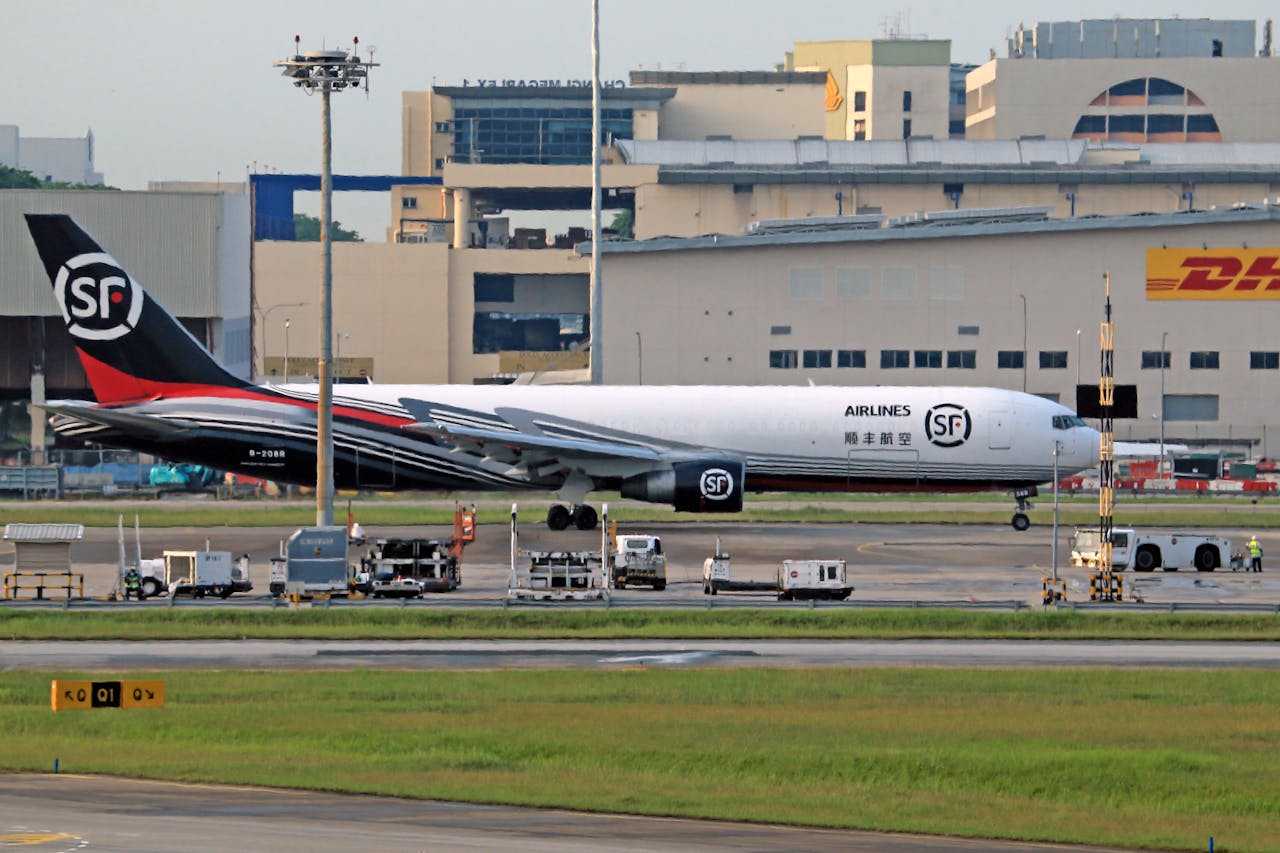 SF Airlines cargo aircraft parked on the airport tarmac near a DHL building.